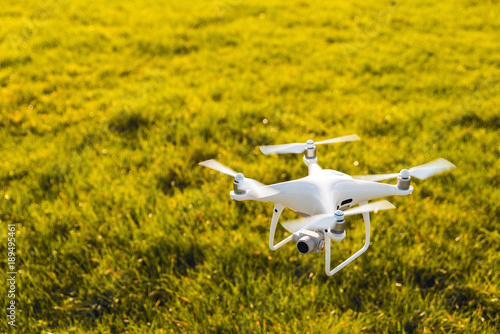 Picture of flying white drone camera in front of paddock