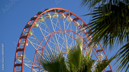 Amusement park ferris wheel slowly turning against blue sky photo