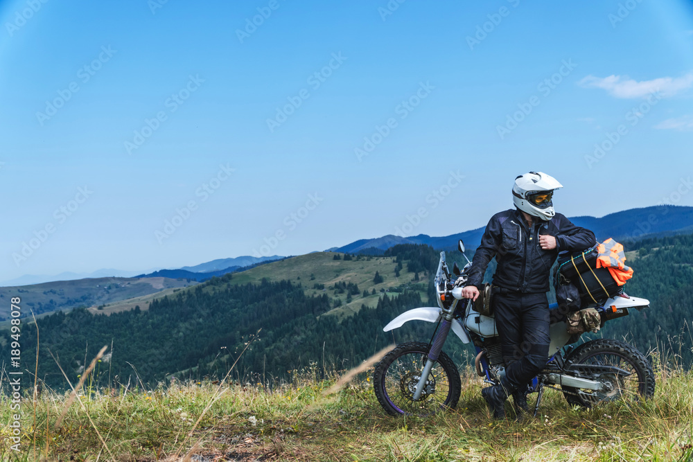 travel motorcycle off road Motorcyclist gear, A motorcycle driver looks at the mountains and coniferous forest, concept, active lifestyle,
