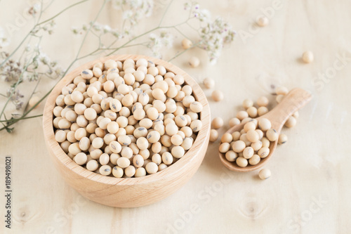 Soybeans in wooden cup and wooden spoon on wood table