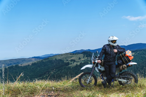 travel motorcycle off road Motorcyclist gear, A motorcycle driver looks at the mountains and coniferous forest, concept, active lifestyle,