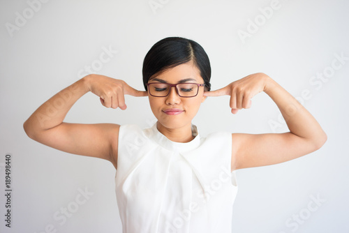 Fotografie Careless businesswoman plugging ears with fingers