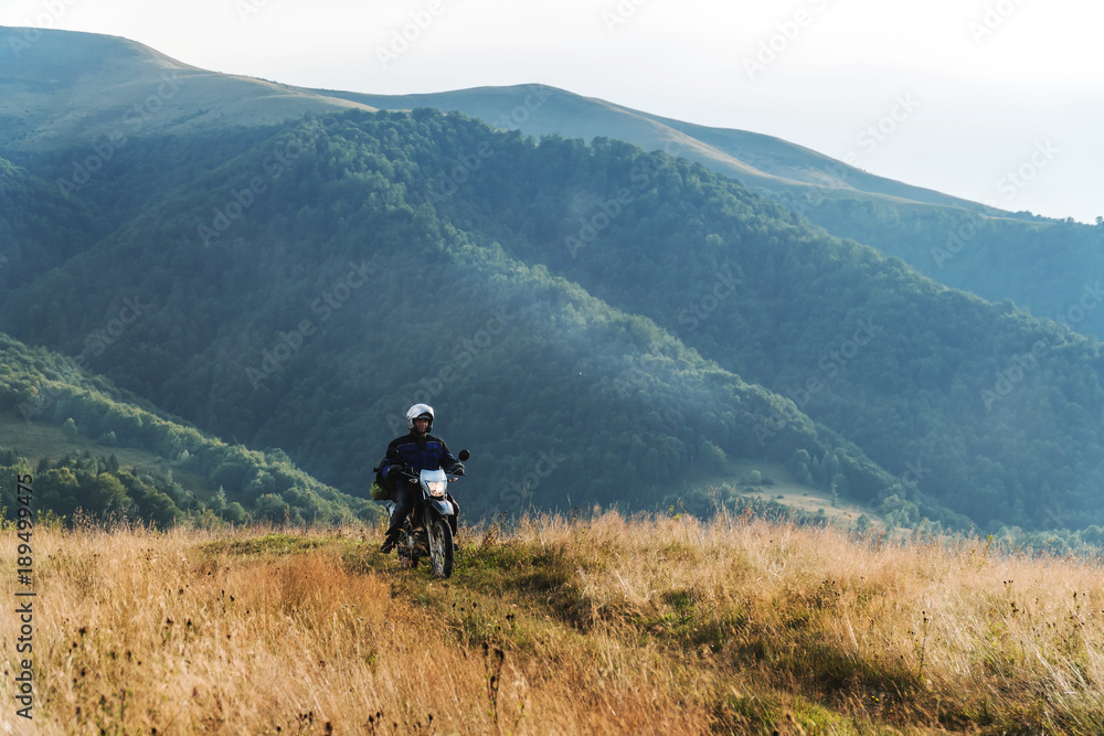 Motorcyclist on a mountainous road, cold overcast weather. Extreme sport, active lifestyle, adventure touring concept. High mountains, dirt roads. enduro off road touring