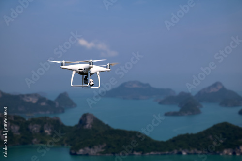 Flying Drone camera or UAV in the blue sky with ocean and island views on the mountain