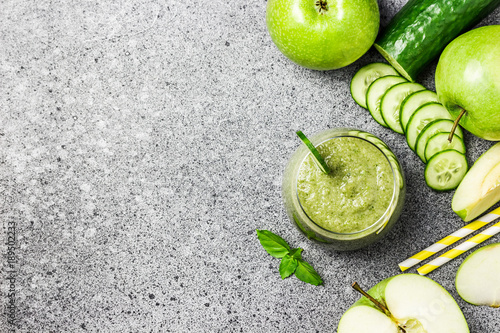 Refreshing cucumber green apple smoothie in a glass on concrete background. Top view, copy space.