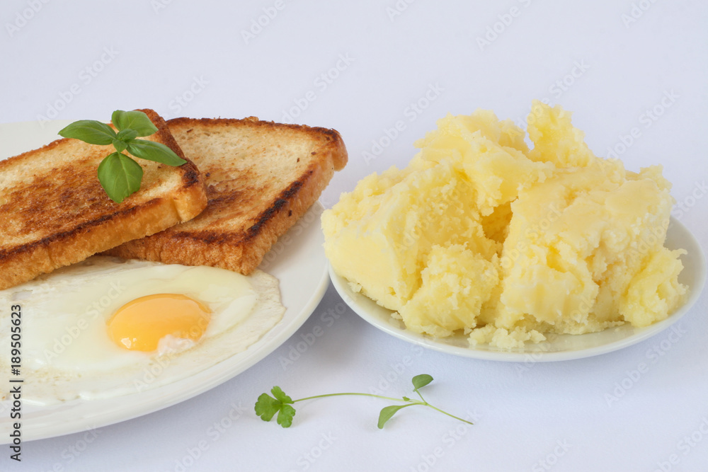 scrambled eggs with herbs and toasts on the white porcelain plate, mashed potatoes, white background scrambled eggs with herbs and toasts on the white porcelain plate, mashed potatoes, white background