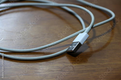 Used USB plug with cable on the wooden floor. universal serial bus, a standardized technology for attaching peripheral devices to a computer.