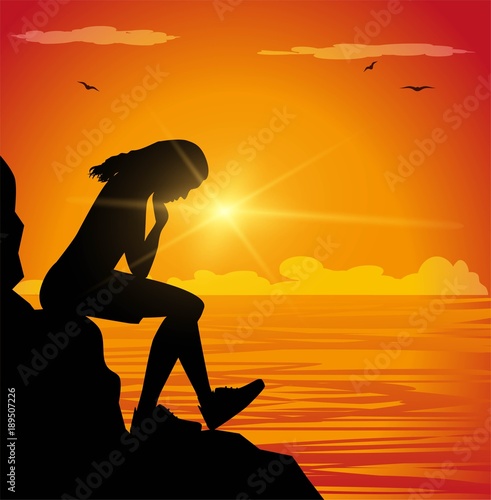 Sad girl sitting on a cliff facing the sea
