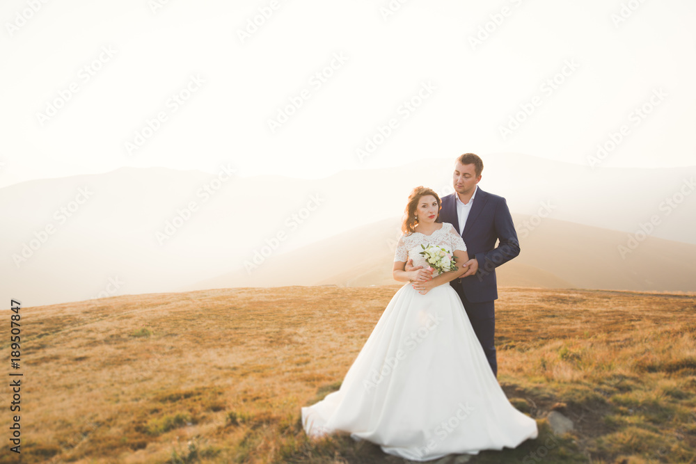 Happy wedding couple posing over beautiful landscape in the mountains