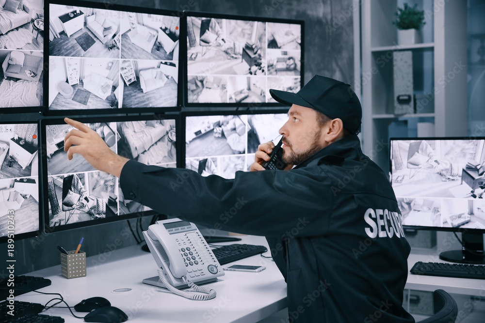 Male security guard using radio transmitter in surveillance room Stock Photo Adobe Stock