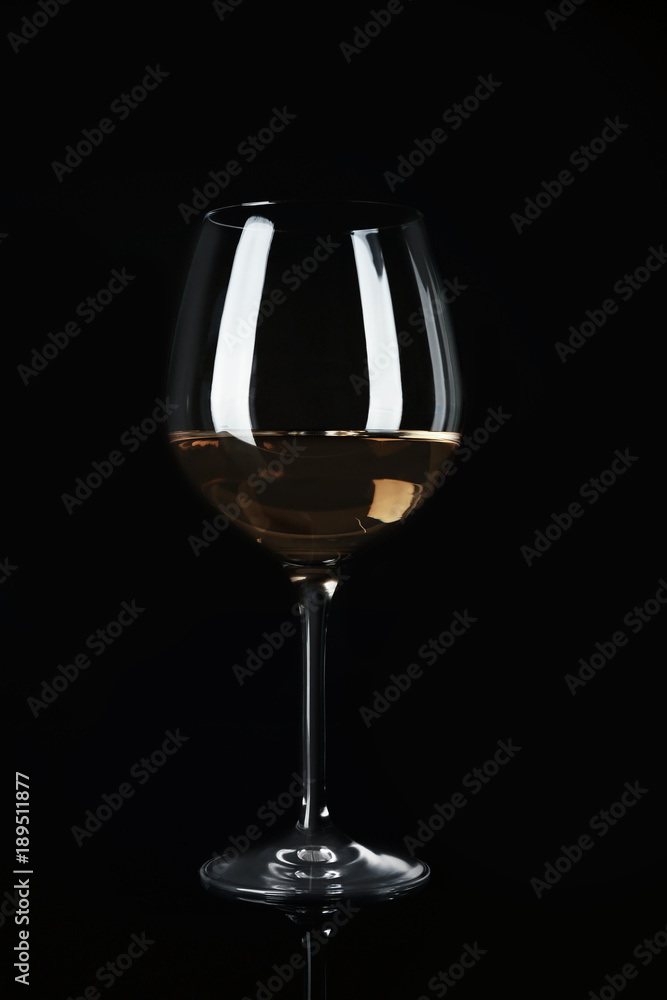 Glass with white wine on black background