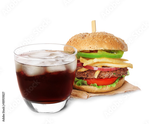 Glass of cold cola with tasty burger on white background