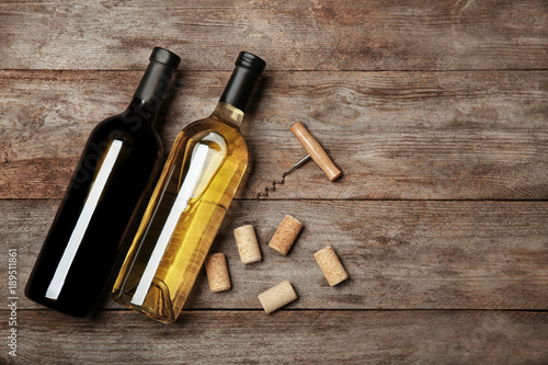 Two bottles with red and white wine on wooden background © Africa Studio