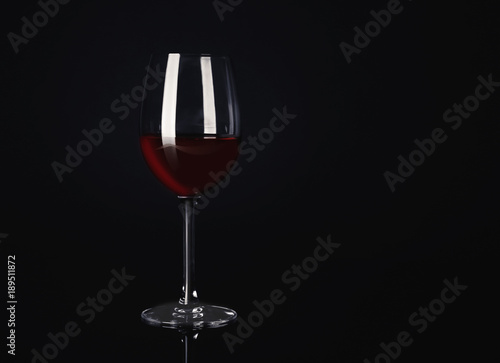 Glass with red wine on black background