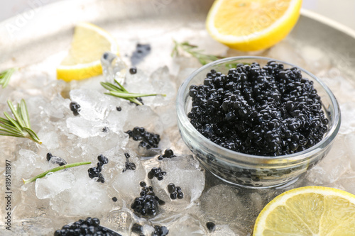 Black caviar served with ice and lemon on metal plate