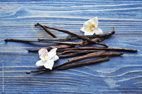 Vanilla sticks and flowers on wooden background