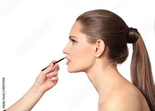 Professional visage artist applying makeup on woman's face on white background