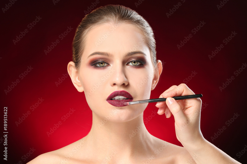 Obraz premium Professional visage artist applying makeup on woman's face on dark background