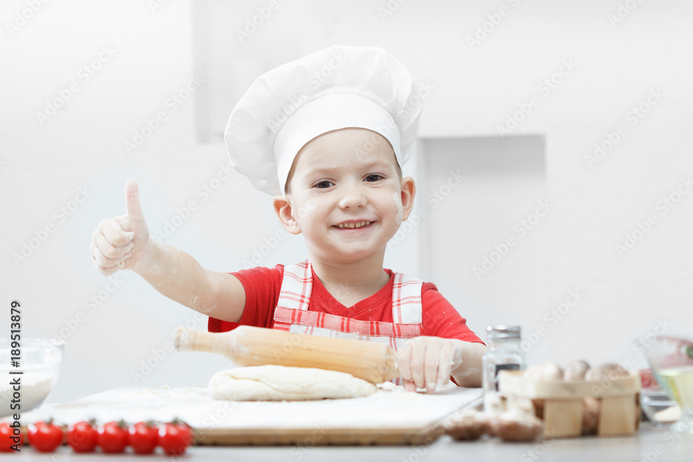 Boy with chef hat preparing the pizza dough Boy with chef hat preparing the pizza dough