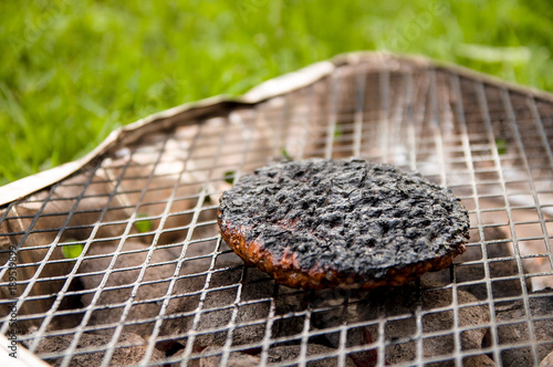Close-up of a burned burger on a grill in the park. Selective focus.