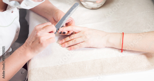 Manicure. Master applies varnish drawing on nails gel in spa . Closeup finger nail care by specialist in beauty salon.