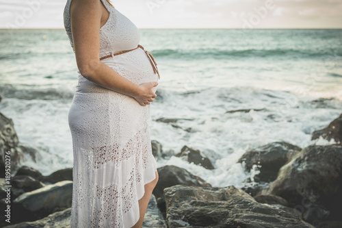 Mujer embarazada tocandose la barriga en la playa