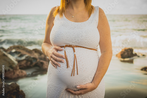 Mujer embarazada tocandose la barriga en la playa