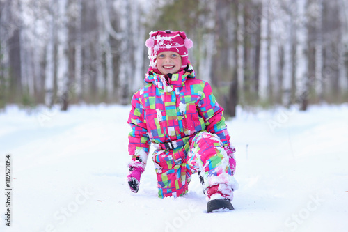 Funny happy little girl walks on a large drifts in the winter forest