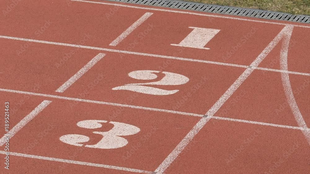 Close-up view of empty running track with white lines and numbers, stadium Close-up view of empty running track with white lines and numbers, stadium
