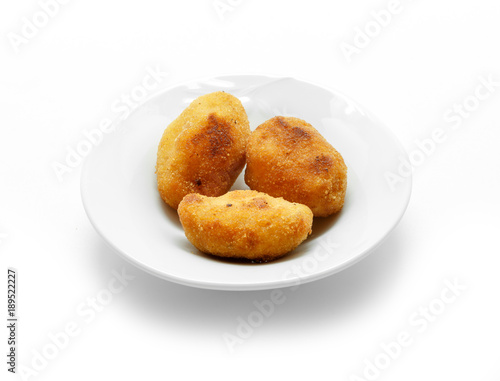 Homemade traditional Spanish croquettes on a white plate and isolated on white background.