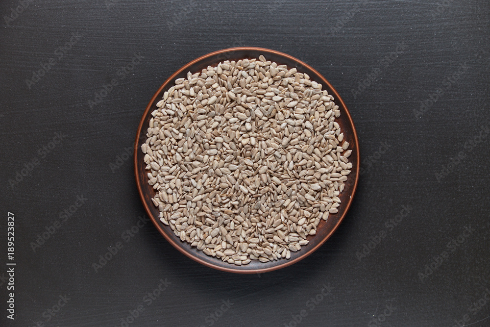 Sunflower seeds in a plate on a black background, top view. Sunflower seeds in a plate on a black background, top view.