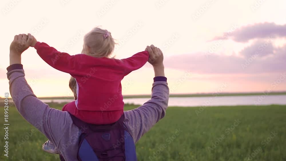 Father carrying daughter on his shoulders and plays with her. During sunset in a field Father carrying daughter on his shoulders and plays with her. During sunset in a field