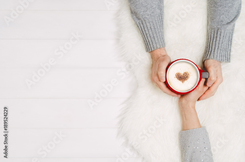 Couple in love holding hands with coffee on white wooden table. Photograph taken from above, top view with copy space