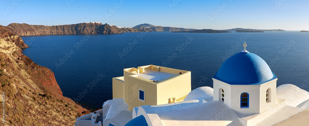 Obraz premium Panoramic image of local church with blue cupola in Oia on Santorini island