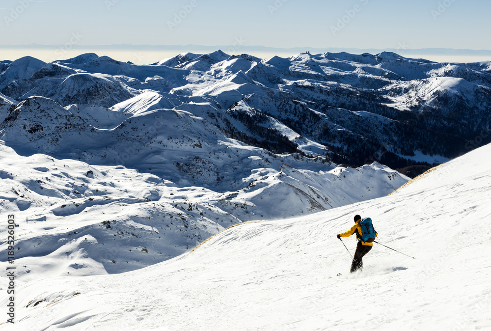 Scialpinista scia scendendo dal pendio innevato nel parco Adamello, Alpi Italiane, Lombardia, Italia.