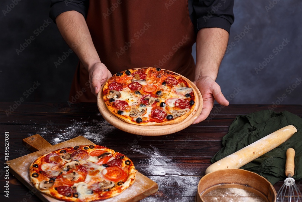 Chef baker with freshly baked pizza. Cooking process, Italian food concept