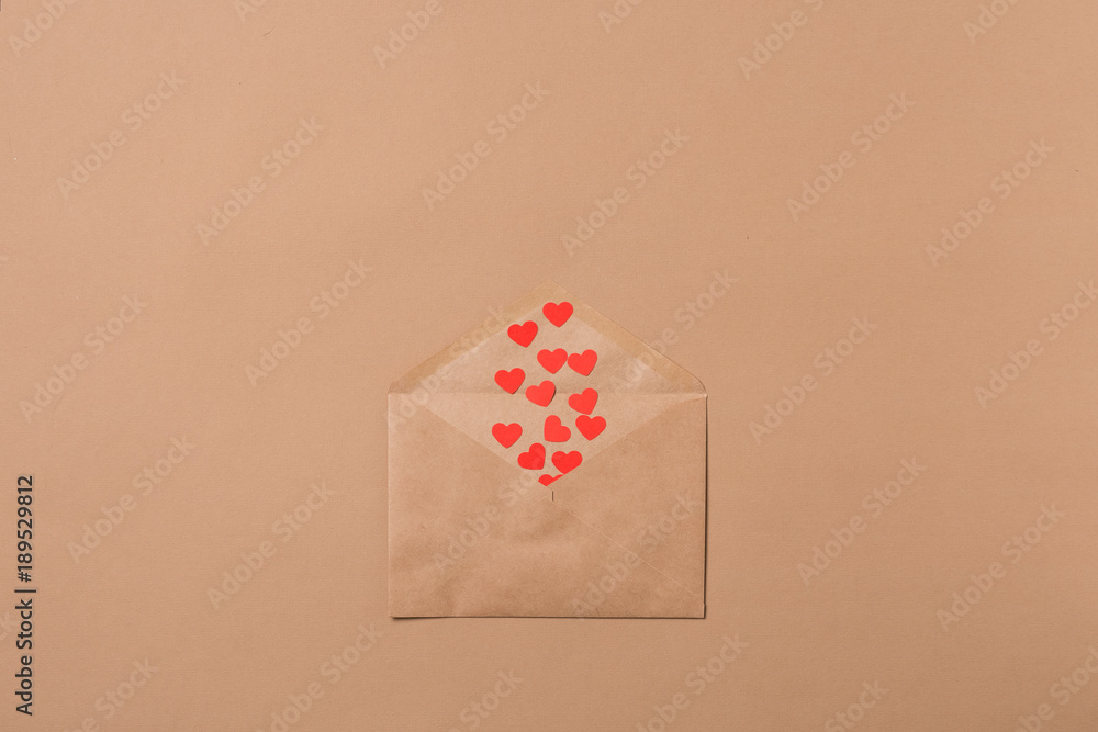 Craft envelope filled with red hearts on a beige background. Love concept. Saint Valentine's Day concept. Mother's day concept.
