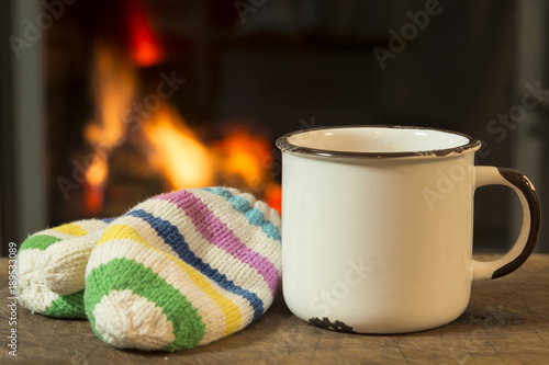 Hot drink and children's knitted gloves to warm and positive mood on the background of a blazing fire in the oven / After playing in the snow