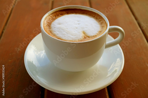 One cup of hot Cappuccino coffee with milk foam served on dark color wooden table 