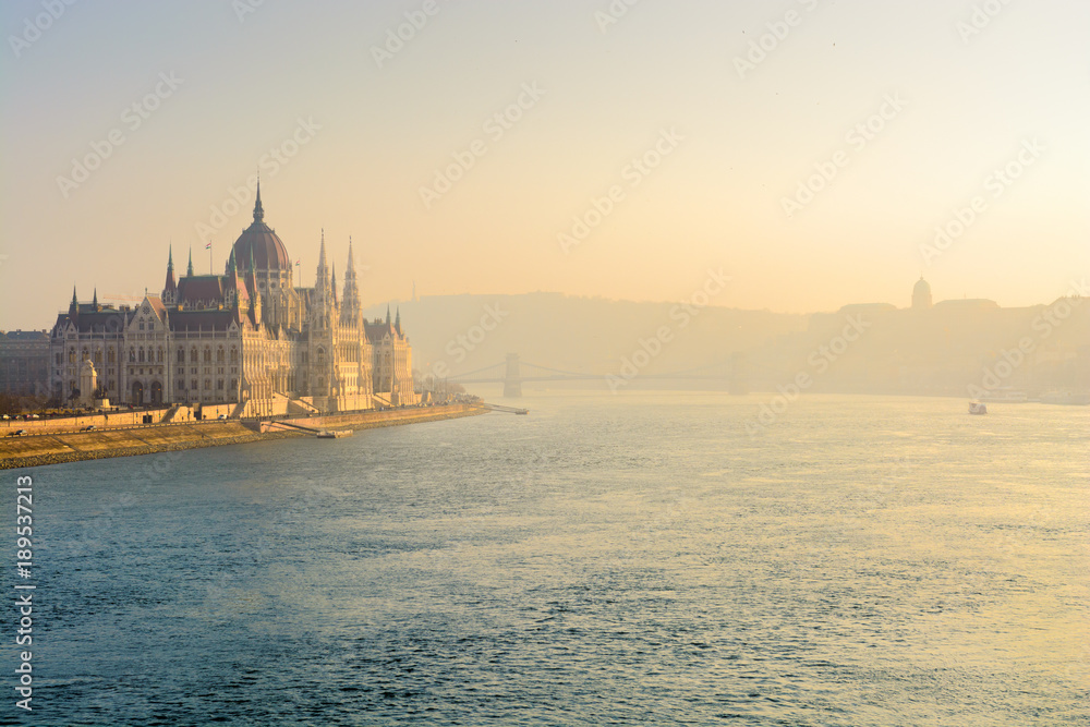 Sunlit Danube river and Parliament building in mist