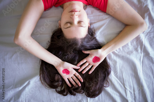 Attractive brunette young woman with drawing heart on hands in the bed photo