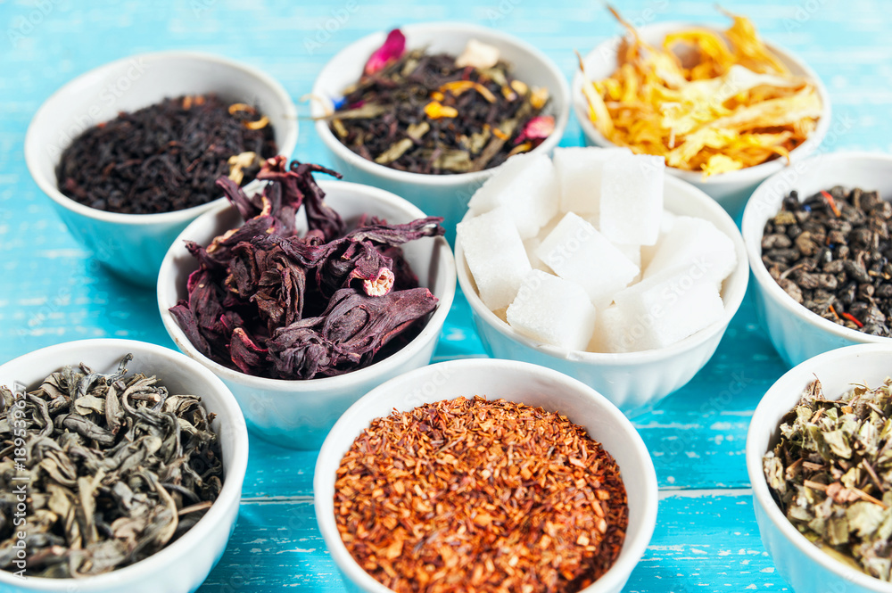 Various dried medicinal herbs and teas in several bowls on blue wooden background Various dried medicinal herbs and teas in several bowls on blue wooden background