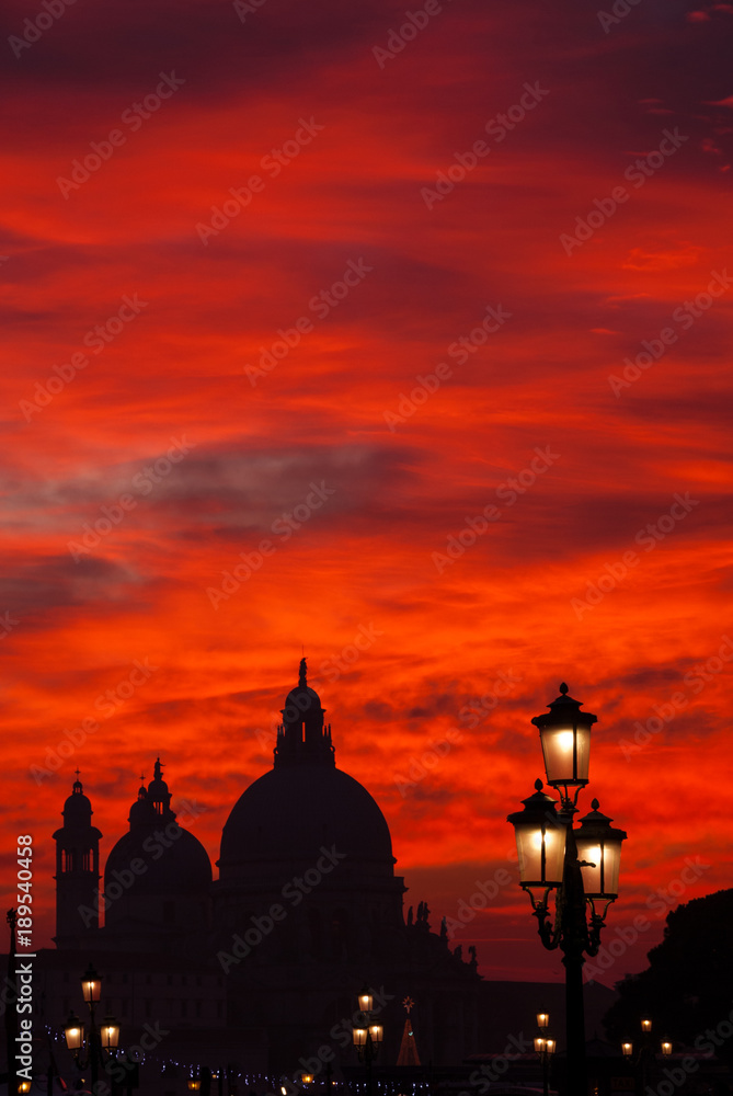 Venice red blood sky sunset with Salute Basilica domes and lamps