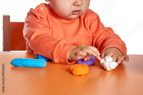 Child hands playing with colorful clay. Isolated on white background