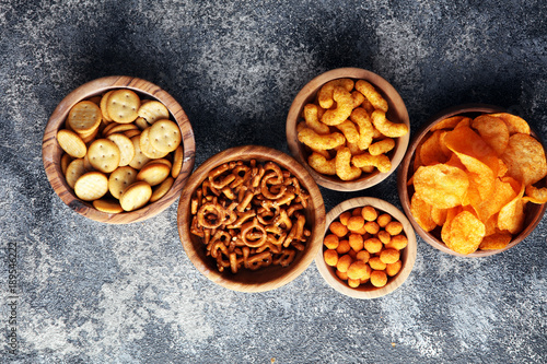 Salty snacks. Pretzels, chips, crackers in wooden bowls. © beats_