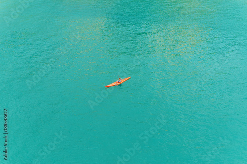 human in red kayak in the middle of the blue sea top view
