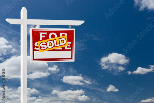 Right Facing Sold For Sale Real Estate Sign Over Blue Sky and Clouds With Room For Your Text.