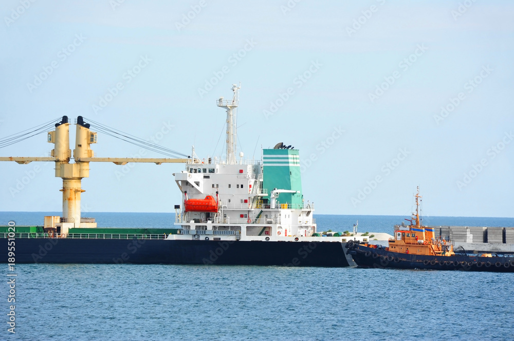 Fototapeta premium Tugboat assisting bulk cargo ship