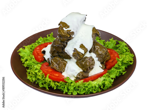 Dolma with white sauce and tomatoes.Stuffed vine leaves.  photo