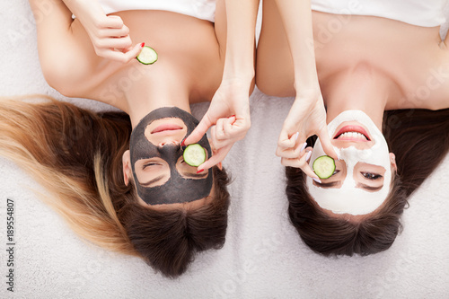 A picture of two girls friends relaxing with facial masks on over white background